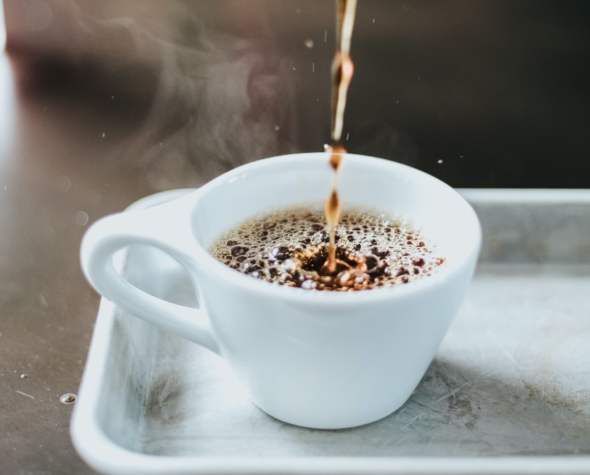 A white mug filling up with coffee.